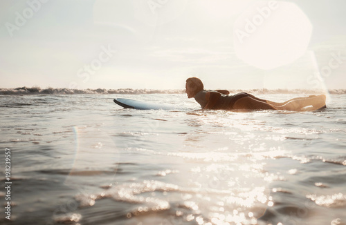 Woman surfer floating on the long surfboard towards line up