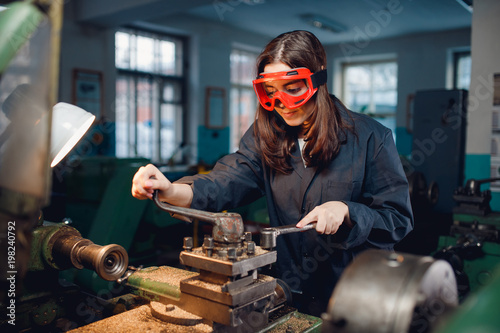 Young woman student works on an automatic lathe CNC, industrial workshop. Concept vocational education turner. photo