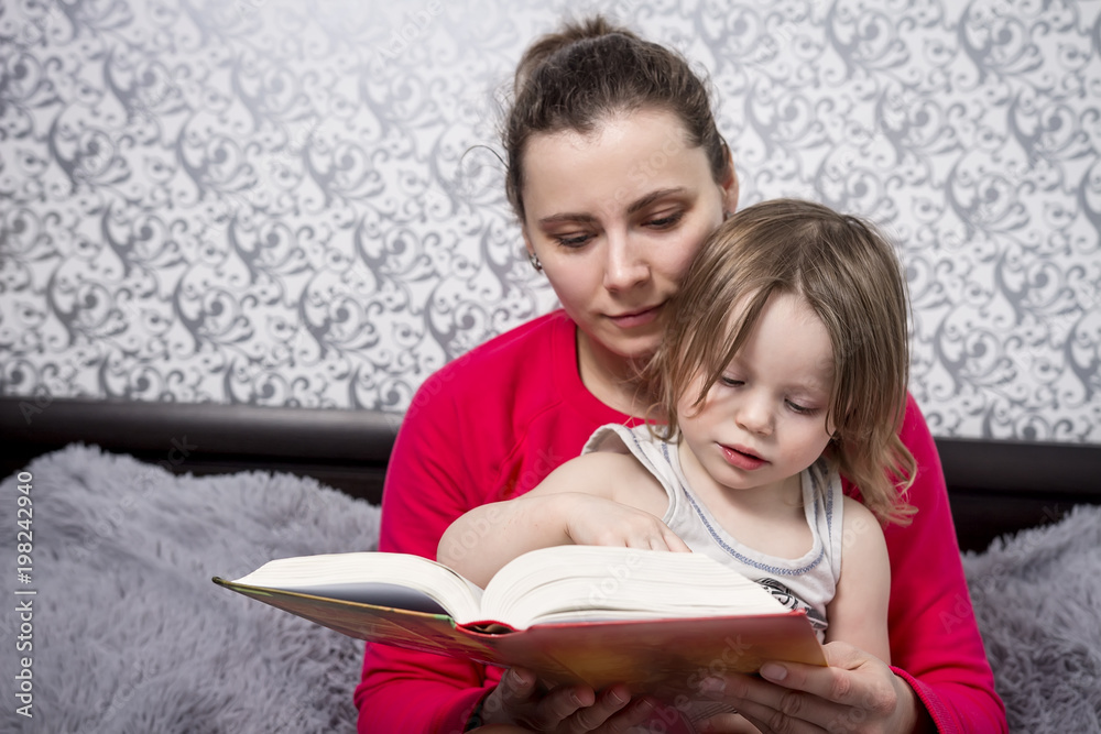 Young mother and little daughter read fairy tale books. Family concept. Spending time with children. Mom and daughter at home reading a book. The child listens to the story that mother reads. Young mother and little daughter read fairy tale books. Family concept. Spending time with children. Mom and daughter at home reading a book. The child listens to the story that mother reads.