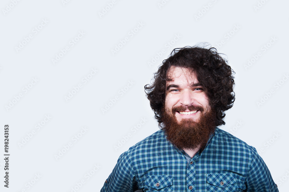 Smiling happy man with beard and curly hair on white background. Portrait of cheerful bearded hipster man. Young man looking confident at the camera. Smiling happy man with beard and curly hair on white background. Portrait of cheerful bearded hipster man. Young man looking confident at the camera.