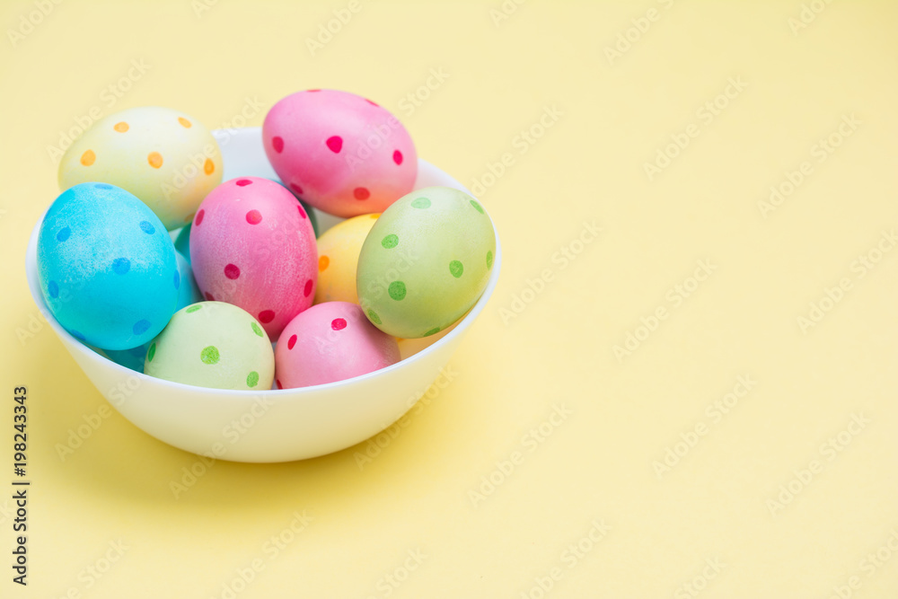 Happy Easter concept. Colorful polka dot eggs in cup on pastel yellow background. Minimal concept. Design, visual art.
