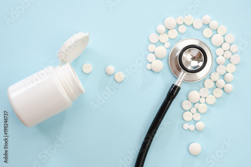Concept medical of exam, diagnosis and treatment, stethoscope on blue background with mix pills