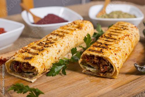 Turkish Adana wrap kebap on wood with appetizer