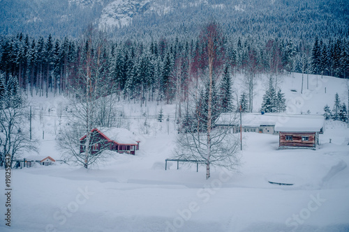 Outdoor view of traditional Norwegian mountain red houses of wood covered with snow in stunning nature background in Norway photo