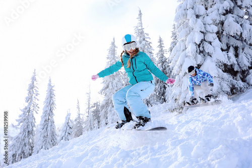 Snowboarders on ski piste at snowy resort. Winter vacation