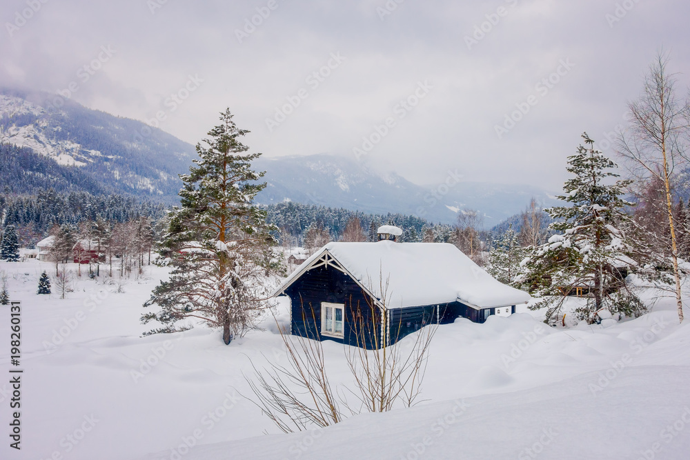 View of traditional mountain wooden houses covered with snow in stunning nature background in Norway