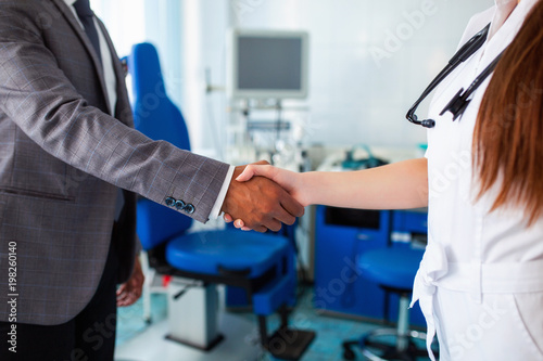 A beautiful female doctor holds the Asian patient's hand for encouragement and sympathy and touching her hand. The concept of partnership, trust and medical ethics. Bad news and support.