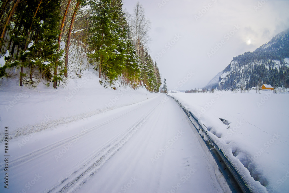 Outdoor view of winter road covered with heavy snow and ice in the forest of Norway