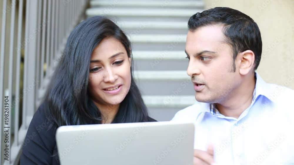 Closeup portrait of two businesspeople having discussion using digital devices, isolated stairs background outside Closeup portrait of two businesspeople having discussion using digital devices, isolated stairs background outside