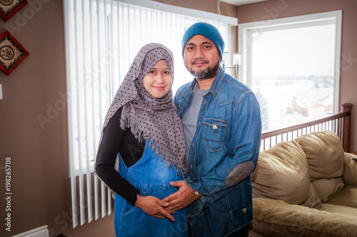 A husband with his pregnant wife inside their home during winter in Canada