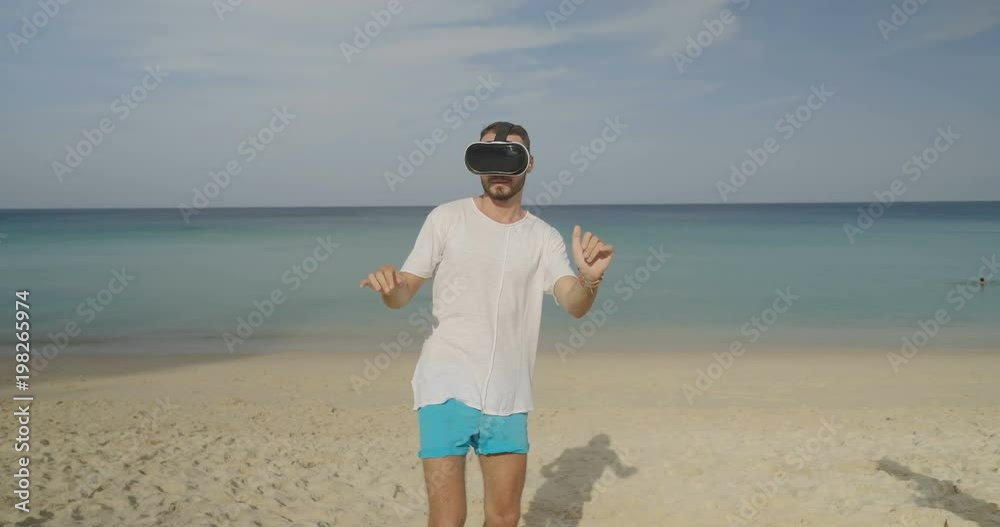 Young man using virtual reality glasses meeting his date beautiful woman on the tropical beach over beautiful sea and sky background Young man using virtual reality glasses meeting his date beautiful woman on the tropical beach over beautiful sea and sky background