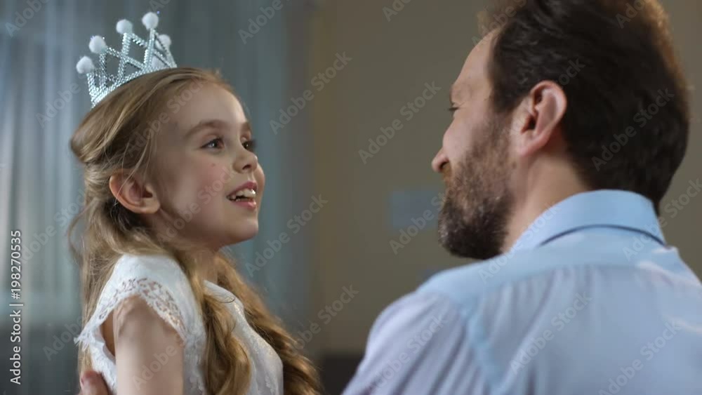 Cute little girl in princess crown dress hugging father, tender relations, party Cute little girl in princess crown dress hugging father, tender relations, party