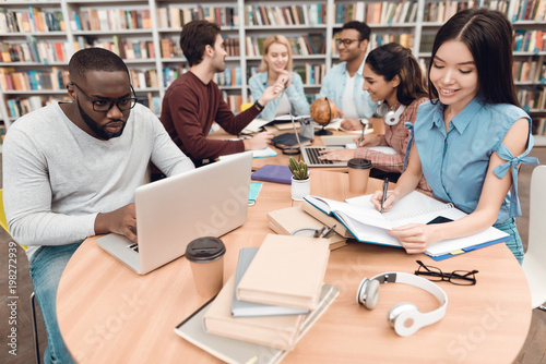 Fotografie Six ethnic students, mixed race, indian, asian, african american and white surrounded with books at library