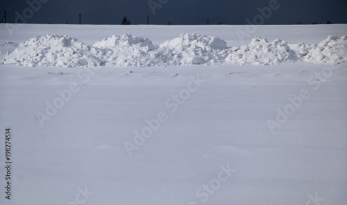 snow field. The plain is covered with white snow under a blue sky with thick white clouds. before a snowfall, a storm, a snowstorm. premonition of a blizzard. in anticipation of a blizzard. © Оксана Скиданова
