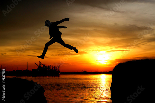 Silhouette of a man jumping over the cliff