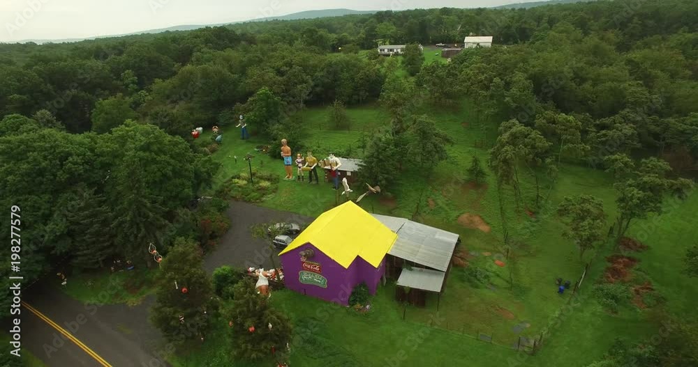 Low altitude, orbiting aerial views of an eccentric’s collection of giant American roadside attractions and oddities like Muffler Man, Brian the Beach Boy, giant apple, crab, the Simpsons riding a tra