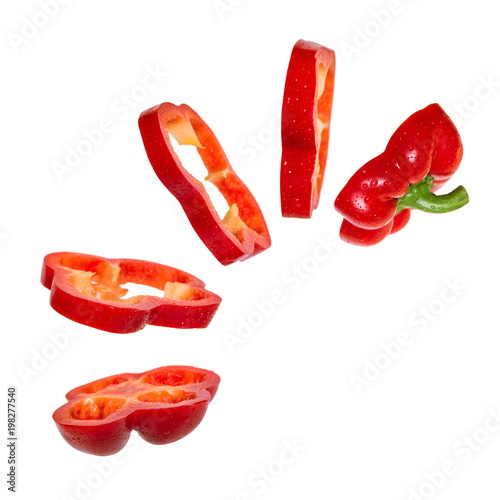 Creative concept with flying red paprika. Sliced floating pepper. Levity capsicum vegetable isolated on white background