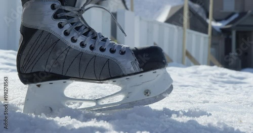 Hockey player repositions skate in snow beside out door hockey rink - ready to play photo