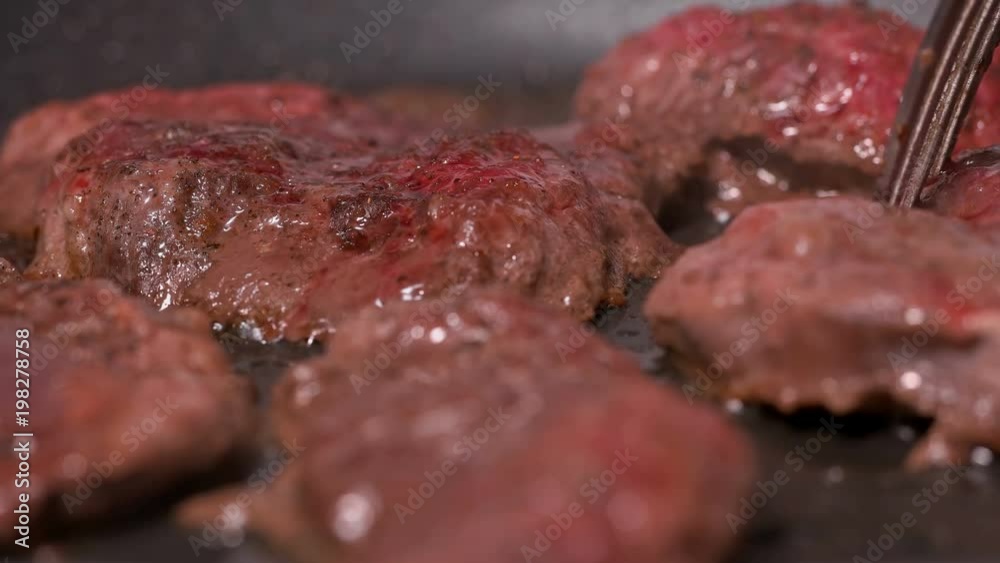 cook checks and moves pieces of meat that is fried in a pan cook checks and moves pieces of meat that is fried in a pan