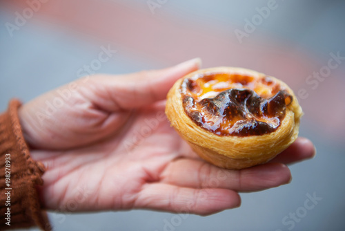 Sweet egg tart custard pie on woman's hand
