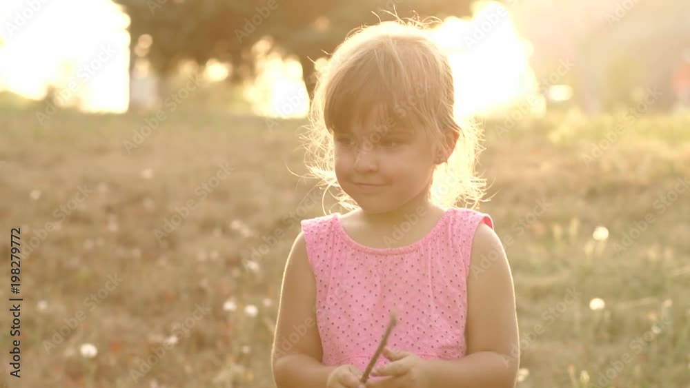 Portrait of a little girl in the Park in the background of the setting sun, she screams loudly. Silhouette of a little girl on the background of the setting sun. Slow motion. Portrait of a little girl in the Park in the background of the setting sun, she screams loudly. Silhouette of a little girl on the background of the setting sun. Slow motion.