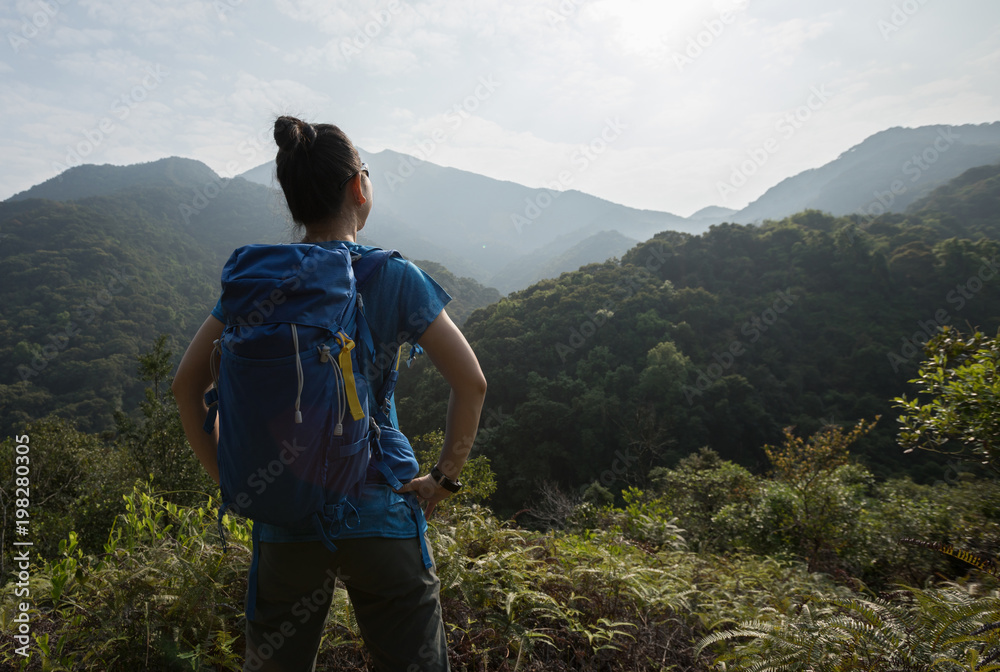 woman backpacker enjoying the view on morning mountain valley