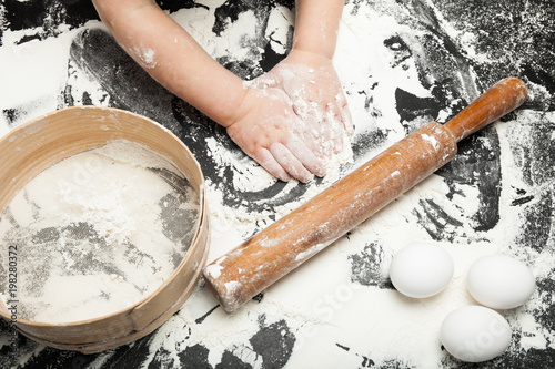 Children's hands knead the dough from flour, close-up.