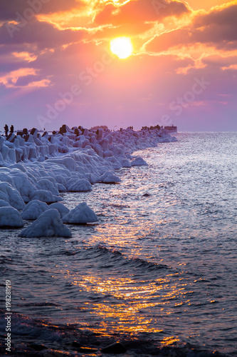 A beautiful evening landscape of a frozen breakwater in the Baltic sea. Winter landscape at the beach. Vivid colors. photo