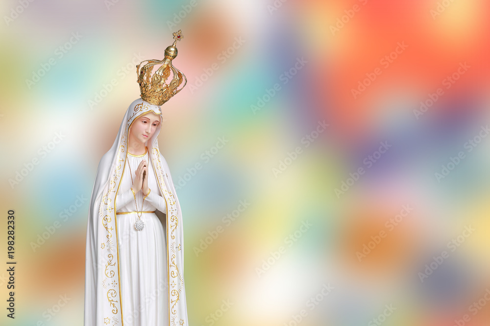 Statue of Virgin Mary in Roman Catholic Church on blur colorful background.