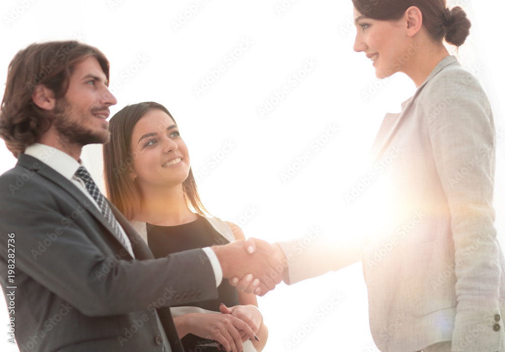 Businesspeople  shaking hands against room with large window loo