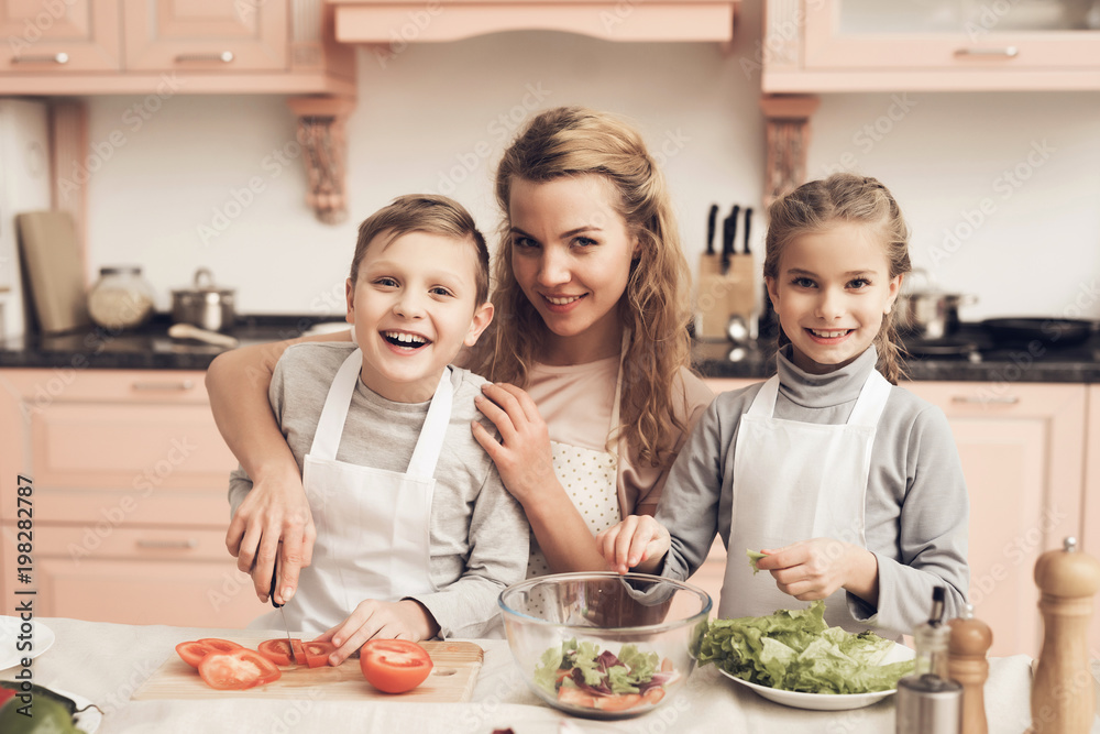Children with mother in kitchen. Mother is helping kids prepare vegetables for salad. Children with mother in kitchen. Mother is helping kids prepare vegetables for salad.