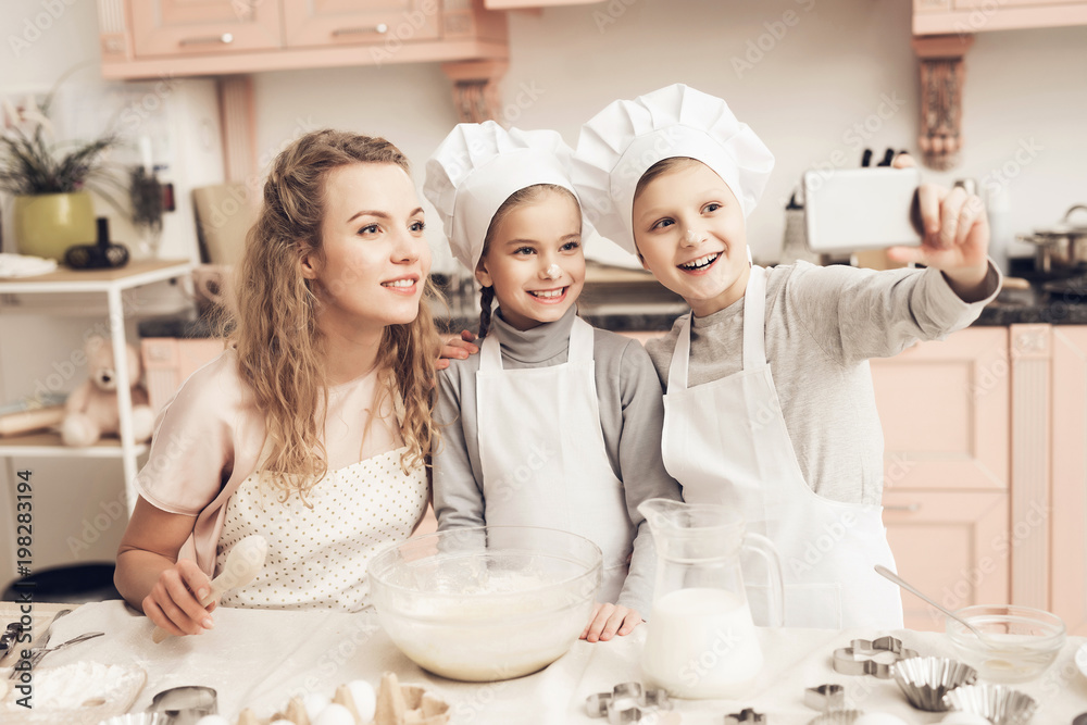 Children with mother in kitchen. Family is taking selfie on phone. Children with mother in kitchen. Family is taking selfie on phone.