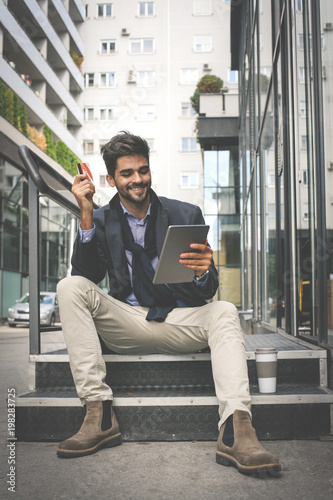 Businessman using credit card and digital tablet.