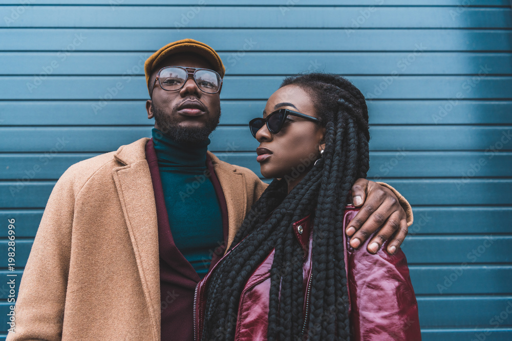 stylish african american couple in fashionable clothes posing together outside