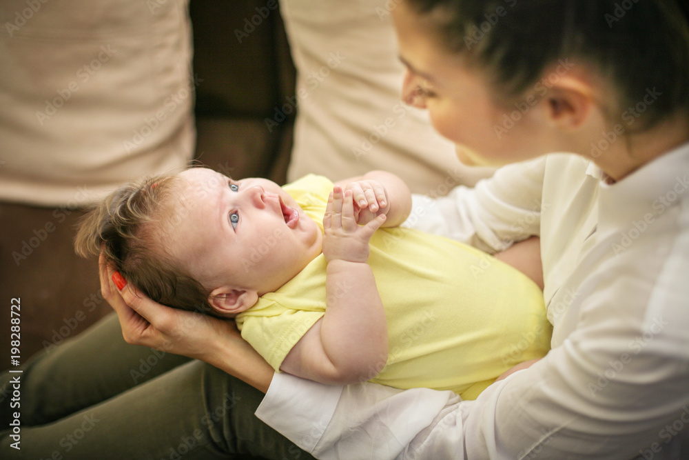 Smiling mother with her baby girl in arms at home. Focus on background. Smiling mother with her baby girl in arms at home. Focus on background.