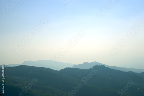 Layer of mountain peaks covered with coniferous deciduous forest in the morning,Morning mountain landscape with waves of fog .
