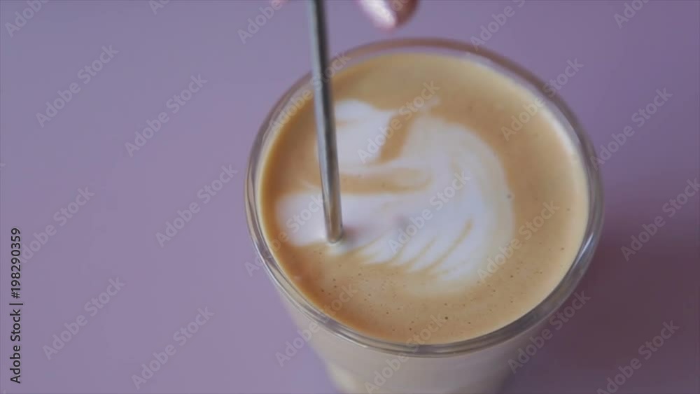 Barista paints milk in a glass with a cappuccino