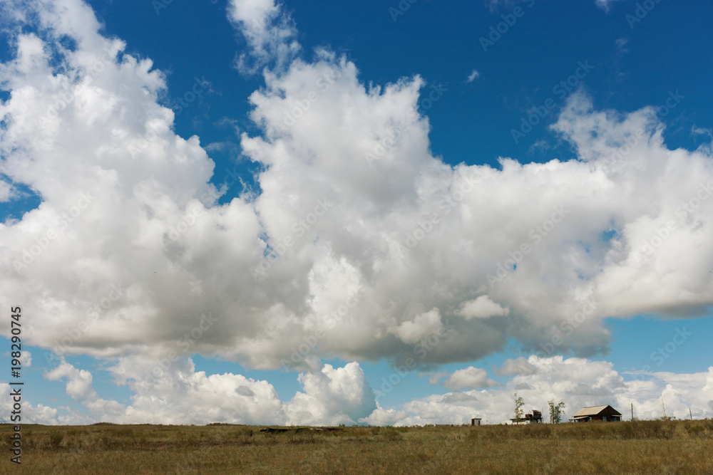 A huge beautiful cloud over a small house. Tyva. Steppe. Sunny summer day. Outdoors