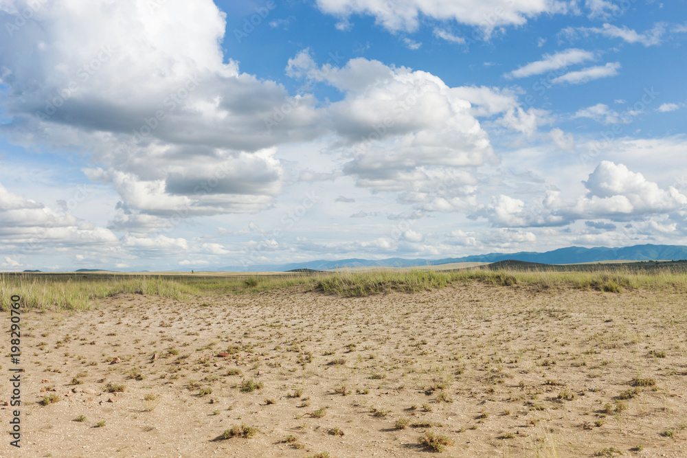 Clouds above the sandy plain near Mongolia. Tyva. Steppe. Sunny summer day. Outdoors
