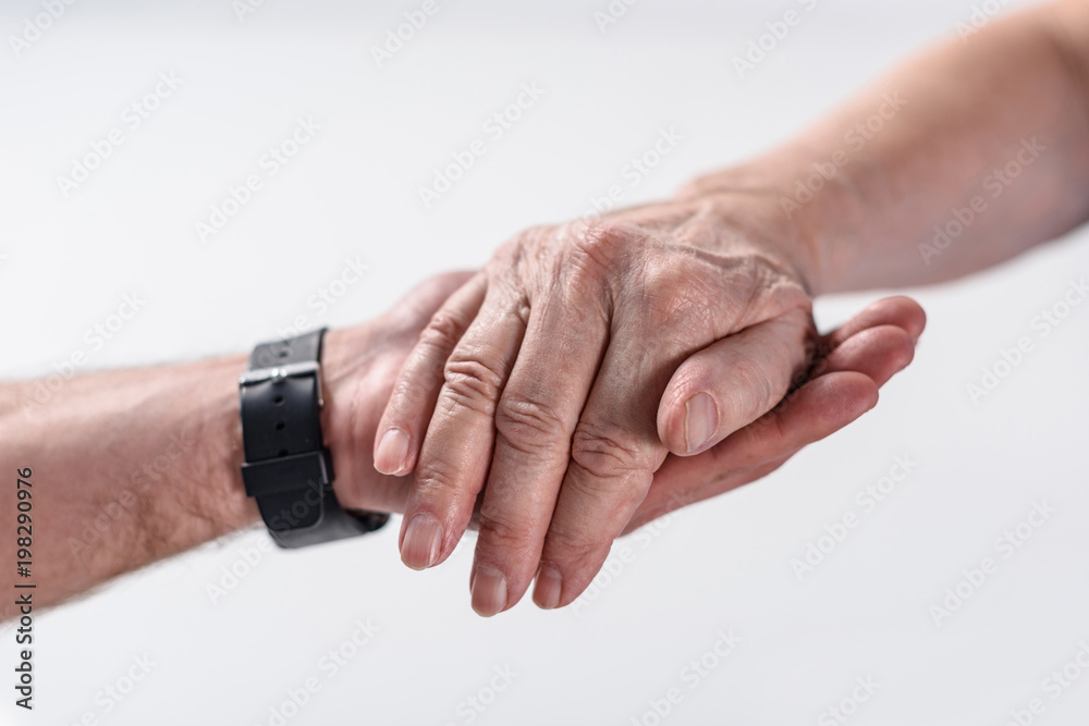 Fototapeta premium cropped shot of senior man and rehabilitation therapist holding hands isolated on grey