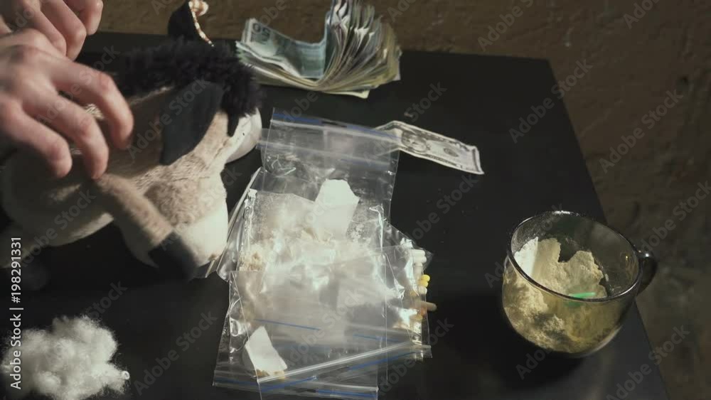 The drug dealer packs drugs heroin, cocaine in packages and weighs them. He takes drugs from