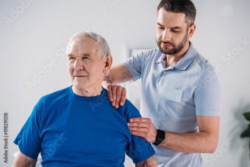 portrait of physiotherapist doing massage to senior man
