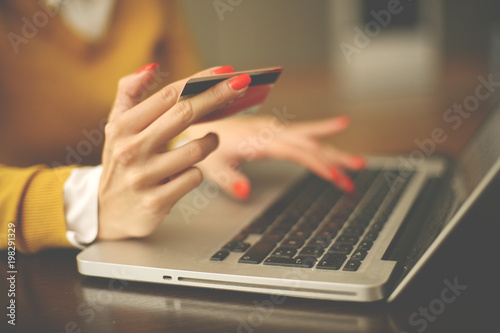 Woman using laptop and credit card. Close up. Focus is on hand.