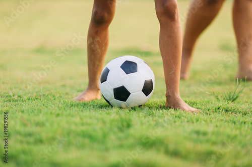 An action and motion picture of an old ball and foot of a kid who is playing football in the sunshine day for exercise.