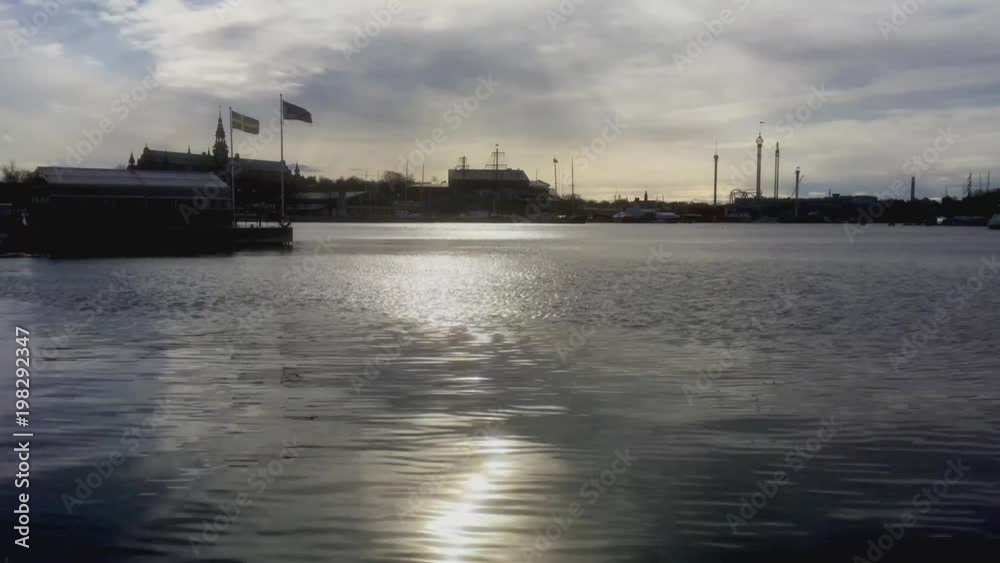 Water in Stockholm, Sweden, withlandmarks and other buildings visible along the coastline. Swedish flag sways in the wind. Water in Stockholm, Sweden, withlandmarks and other buildings visible along the coastline. Swedish flag sways in the wind.