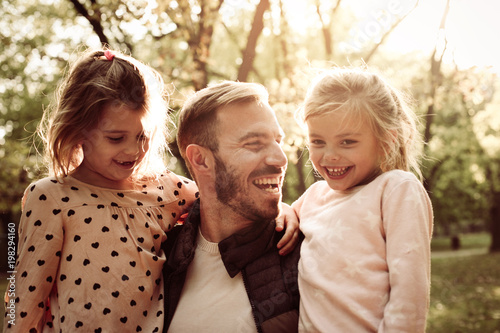 Single father with two little daughters in park.