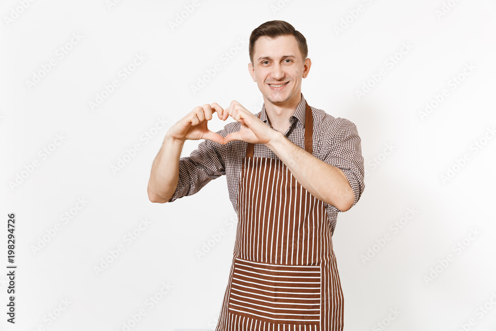 Smiling man chef or waiter in striped brown apron, shirt showing hands shape of heart isolated on white background. Male housekeeper or houseworker - looking camera. Domestic worker for advertisement. Smiling man chef or waiter in striped brown apron, shirt showing hands shape of heart isolated on white background. Male housekeeper or houseworker - looking camera. Domestic worker for advertisement.