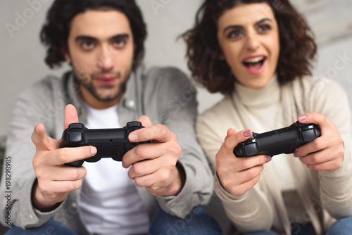 excited young couple playing video game at home