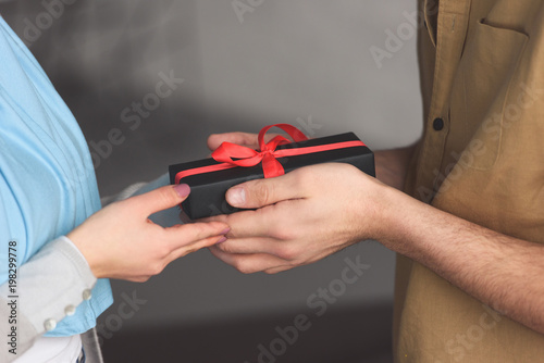 cropped image of muslim boyfriend presenting gift to girlfriend at home