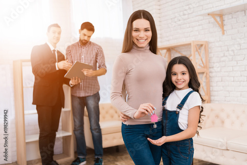 Beautiful mother with her daughter holds keys with key ring in form of house.